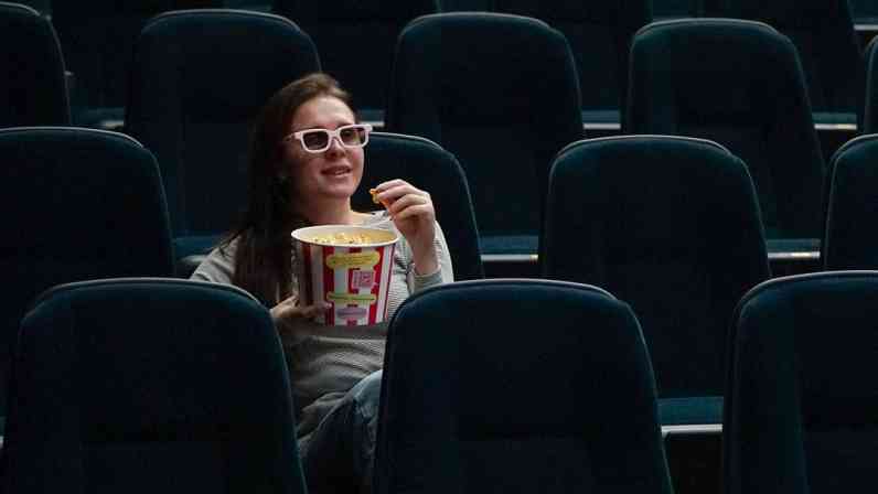 Una mujer con unas palomitas en una sala de cine.